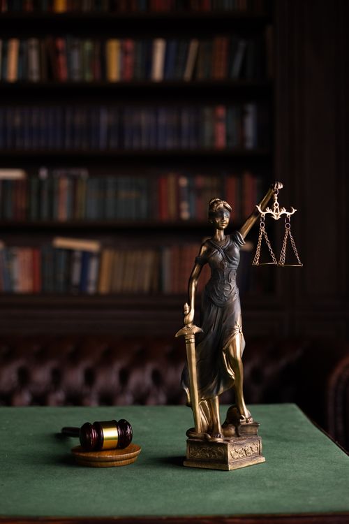 Estatua de la justicia con balanza y mazo sobre una mesa de madera
