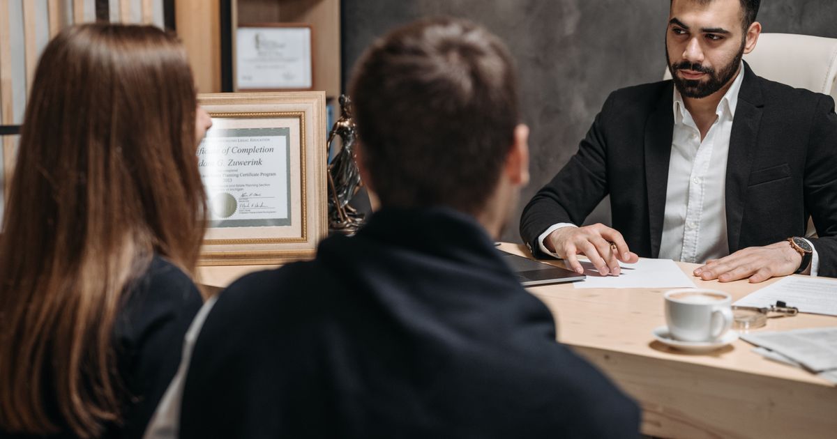 Abogado reunido con clientes en una oficina legal moderna, revisando documentos