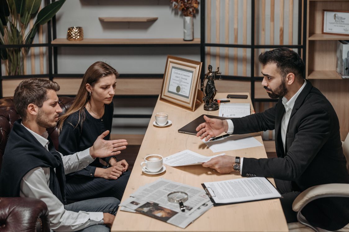Abogado profesional conversando con clientes en su oficina durante una consulta legal