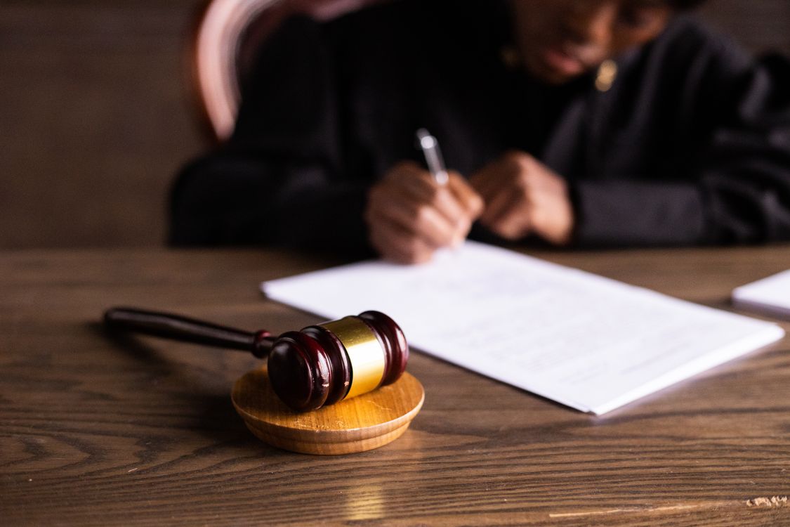 Juez firmando documentos legales en su despacho, representando el proceso judicial penal